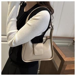 Detail of cream white half-moon shoulder bag with flap closure and leather texture