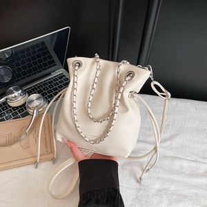 Cream leather bucket bag with chain handle and drawstring closure for urban office style