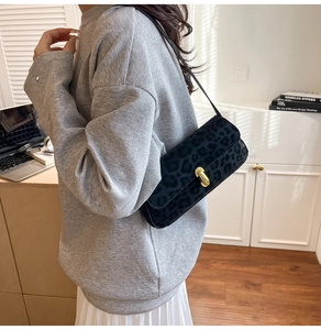 Close-up of black leopard print underarm bag with gold metal buckle and leather strap