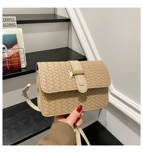 Close-up of beige woven texture and gold metal clasp on a luxury vegan leather bag