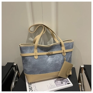 Detail of blue denim and beige leather patchwork tote bag with metal belt buckle lock