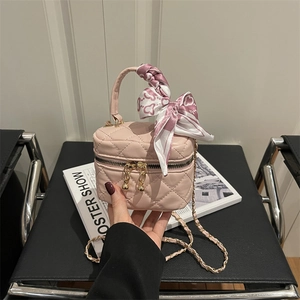 Pink quilted mini handbag with heart print scarf and gold chain strap on a black chair