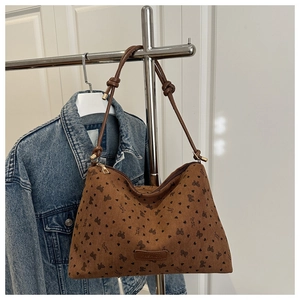Detail of hobo bag featuring black heart prints, bow patterns and leather patch logo