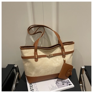 Detail of large tote bag featuring beige textured fabric and brown leather strap with buckle