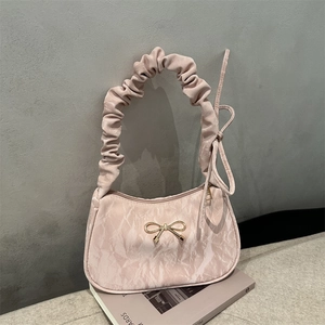 Sac à motif marbre rose avec nœud doré et poignée plissée sur un fond de magazine chic