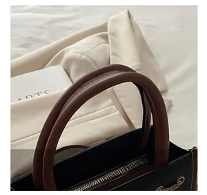 Detail of comfortable brown rolled handles and gold chain on black tote bag