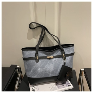 Detail of blue tote bag featuring high-capacity design with gold clasp and black leather trim
