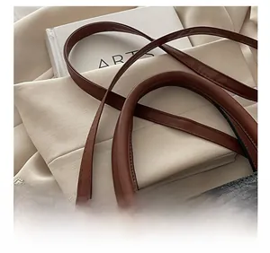 Detail of lychee pattern leather handbag with gold metal logo and decorative chain
