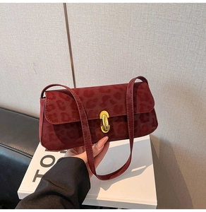 Dettaglio della borsa baguette bordeaux in pelle scamosciata leopardata con chiusura oro