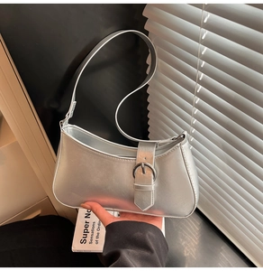 Detail of silver metallic crescent underarm bag with buckle strap and sleek handle