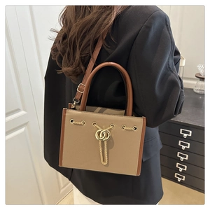 Detailed side view of two-tone tote bag with gold chain and ring buckle on model