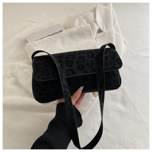 Close-up of black leopard print suede texture and flap design on a crossbody bag