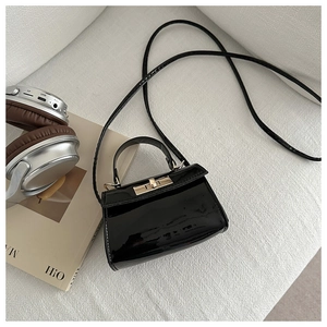 Close-up of a black glossy crossbody bag with elegant gold buckle and mirror finish