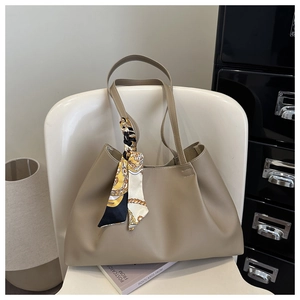 Detail of khaki tote bag with textured leather and decorative printed silk scarf on handle