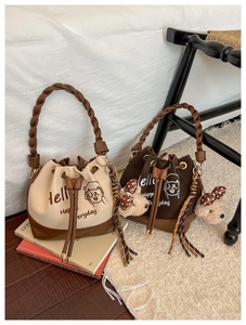 Detail of drawstring bucket bags with letter print and plush pendant in cozy room setting