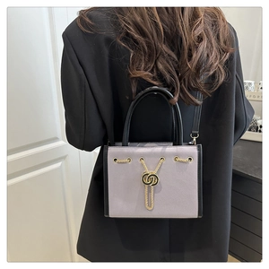 Detail view of lilac pebble leather tote with chain accent on black blazer outfit