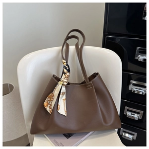 Detail of dark brown tote bag with white contrast stitching and decorative silk scarf