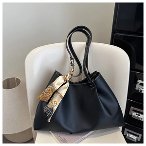 Detail of black tote bag with white contrast stitching and silk scarf on handle