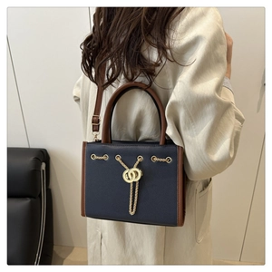 Detail of blue and brown tote bag with gold chain hardware and adjustable shoulder strap