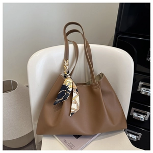 Brown faux leather tote bag with printed silk scarf detail on a white chair