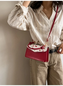 Détail du sac bandoulière imprimé cerise avec poignée nouée rouge et rabat chic