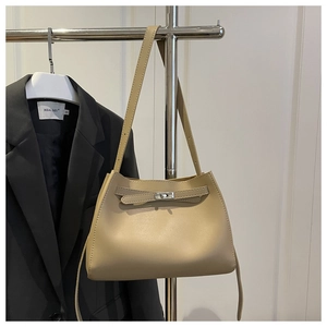 Detalle del bolso trapezoidal beige de PU con hebilla de metal colgado en una percha