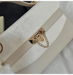 Macro shot of retro metal buckle and gold chain on beige minimalist square bag