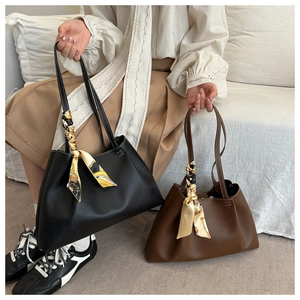 Détail de grands sacs fourre-tout en cuir mat noir et marron avec foulards en soie