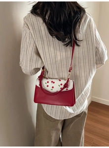 Detailed back view of a red cherry print crossbody bag with knotted handle and strap