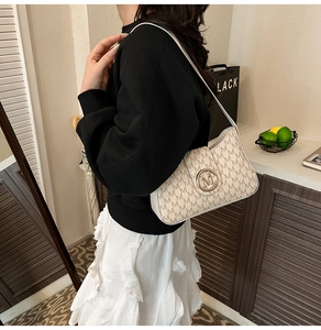 Close-up of vintage shoulder bag featuring ivory monogram leather and gold M logo buckle