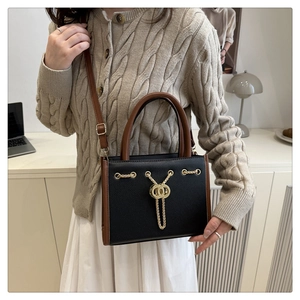 Chic two-tone handbag with gold chain detail shown on a model in a modern lifestyle setting