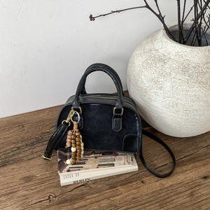 Dettaglio borsa Boston nera con ciondolo in perle di legno e inserti in pelle
