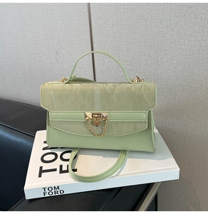 Detail of light green bag with marble texture flap and gold chain lock on white books