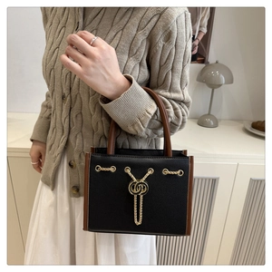 Close-up of elegant black handbag with gold chain detail and textured leather finish