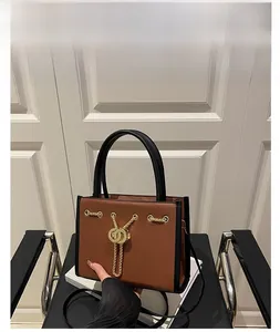 Detail of a brown lychee pattern leather handbag with gold chain and dual ring buckle
