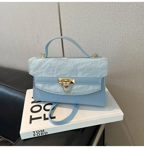 Detail of light blue crossbody bag with marble pattern flap and gold metal buckle
