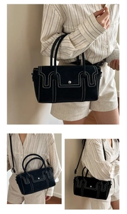 Détail du sac à main noir mat avec surpiqûres blanches contrastées et fermoir en métal rond