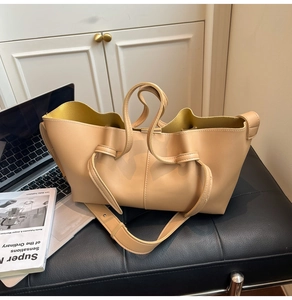 Detail view of beige leather tote bag with pleated design and mustard yellow lining detail