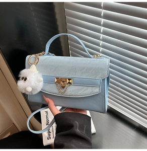 Detail of light blue rectangle handbag with marble texture flap and plush monster charm