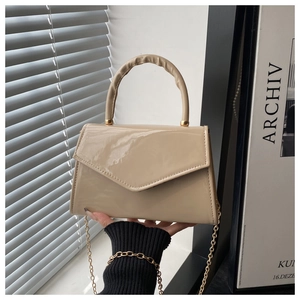 Detail of glossy beige patent leather bag with gold hardware and chain strap