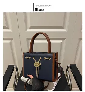 Detail of blue textured tote bag with golden double ring buckle and brown handles