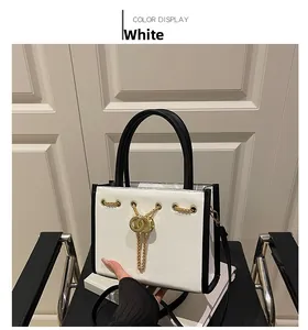 Detailed view of the gold double-ring clasp and chain on the white textured handbag