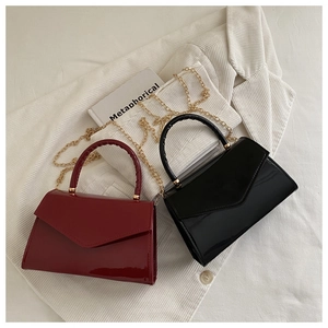 Close-up of glossy patent leather handbags with woven handles and golden chain straps
