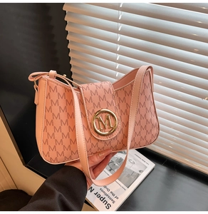 Close-up of pink shoulder bag featuring embossed M pattern and gold metal buckle