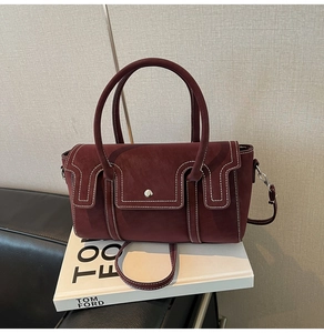 Détail du sac bordeaux avec surpiqûres blanches et fermoir métallique argenté