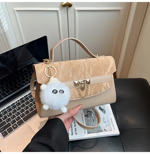 Detail of beige pleated handbag with metal square lock and plush monster charm