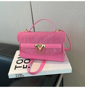 Detail of a bright pink leather crossbody bag with pleated flap and gold metal hardware