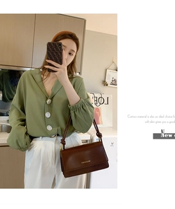 Detail view of a vintage dark brown leather crossbody bag with green cotton shirt outfit