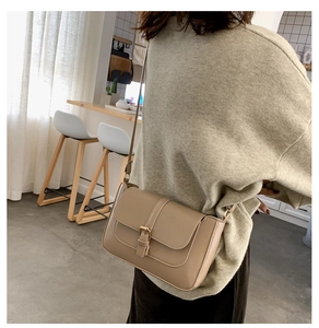 Model showing a beige minimalist crossbody flap bag in a cafe interior setting