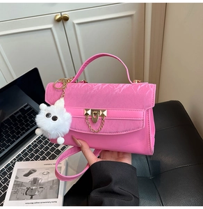 Hot pink leather crossbody bag with gold hardware and white plush doll pendant